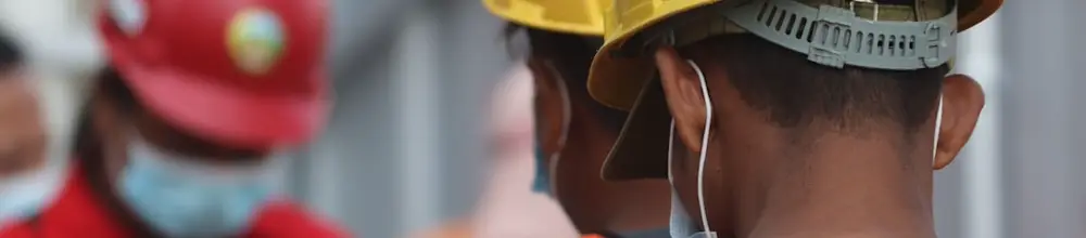 Trabalhadores usando capacete e colete de segurança (EPI) em canteiro de obra